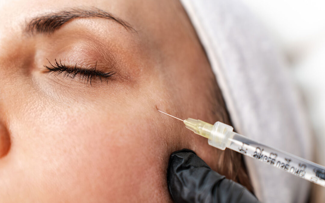 Attractive woman is getting a rejuvenating facial injections at beauty clinic. The expert beautician is filling female wrinkles with botulinum toxin injections or hyaluronic acid fillers.