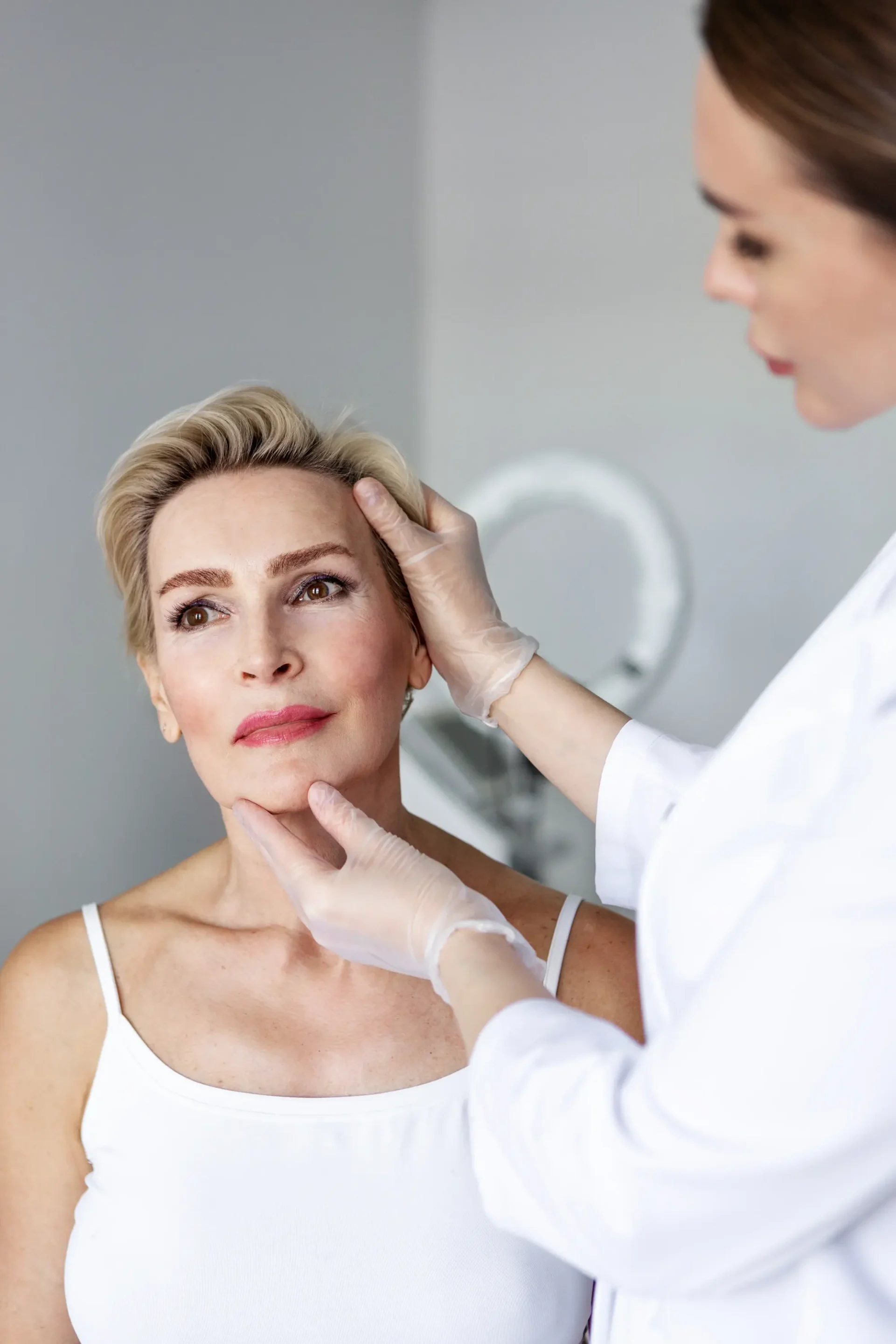 Facial plastic surgeon preparing patient for facelift surgery in medical clinic